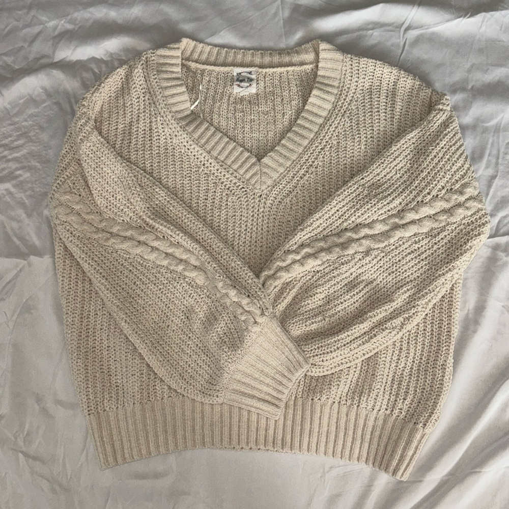 Off-white comfy sweater, designs on the arms, soft fabric, and v-neck neckline